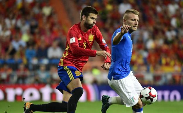 Gerard Piqué disputa un balón con Ciro Immobile,/Afp