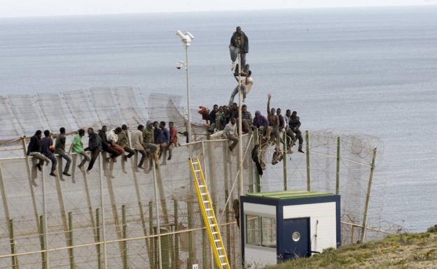 Inmigrantes intentan cruzar la valla de Melilla./Archivo