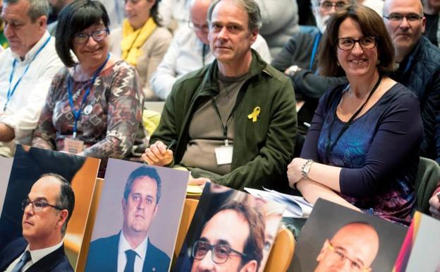 Miembros de la ANC sostienen imágenes de dirigentes políticos catalanes./