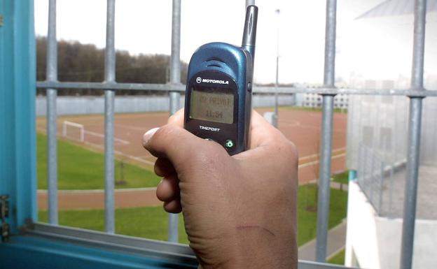 Un preso muestra un teléfono móvil dentro de la celda de una cárcel alemana. /AP