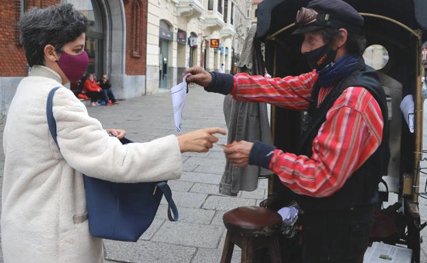 Ángel entrega un cucurucho de castañas a una mujer en su 'parada' de la calle Ancha.