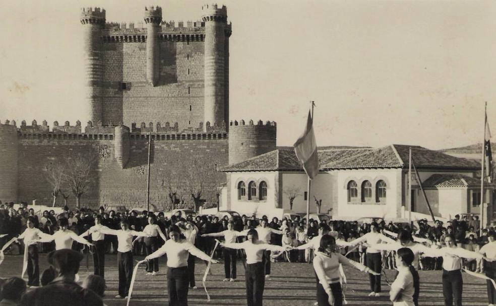 Imagen antigua de Fuensaldaña, con el castillo al fondo y un grupo de jóvenes practicando el juego de las cintas./