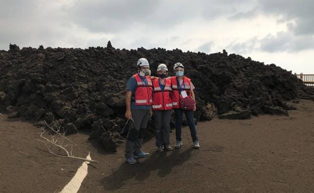 María José Blanco, en el centro, junto a sus dos compañeros del Instituto Geográfico Nacional, posan ante la colada de lava en La Palma./